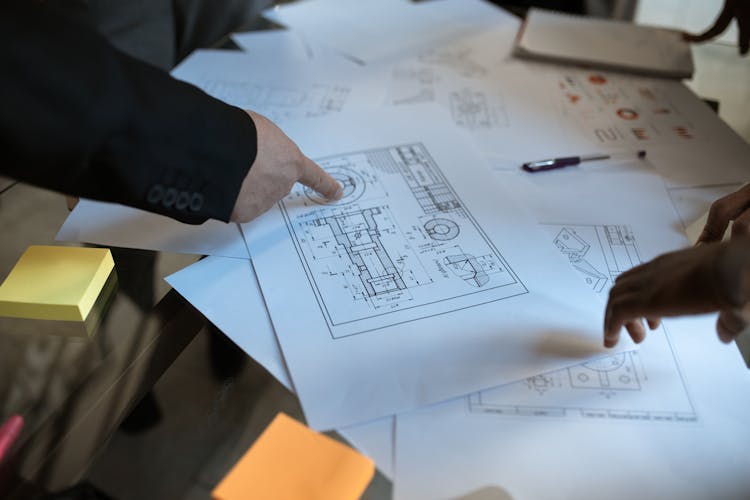 Person Pointing On A Project Plan In Blueprint