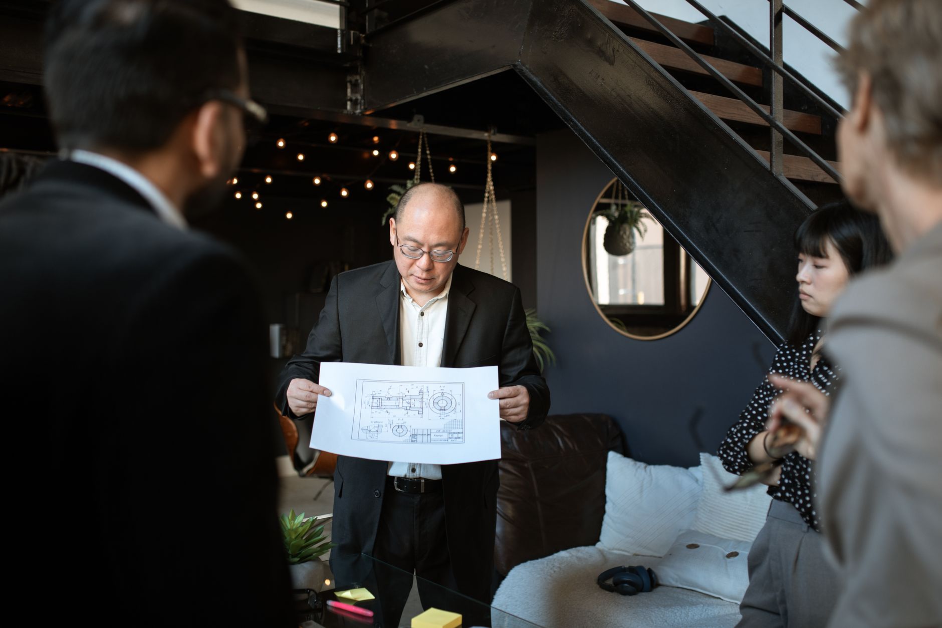 個人品牌服務商品化全攻略:方案設計、範圍定義、交付與SLA A diverse business team discussing a blueprint in a stylish and modern office setting.