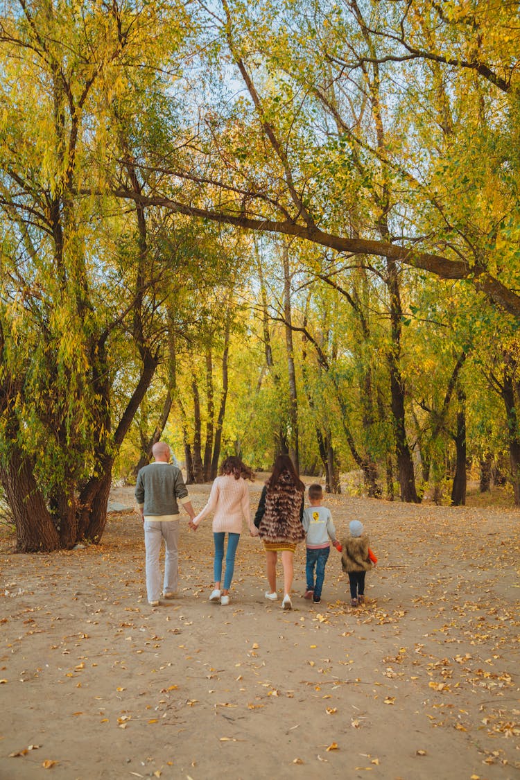 Unrecognizable Family Walking In Autumn Park