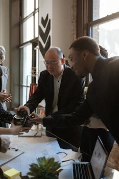 Group of professionals collaborating around a desk in a bright, modern office space.