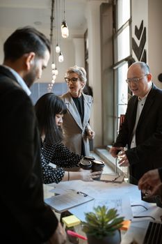 Colleagues in corporate attire having a coffee break meeting indoors.