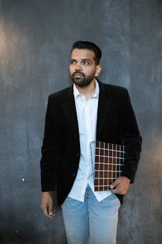 Portrait of a confident man in a suit holding a clipboard, standing against a dark background.