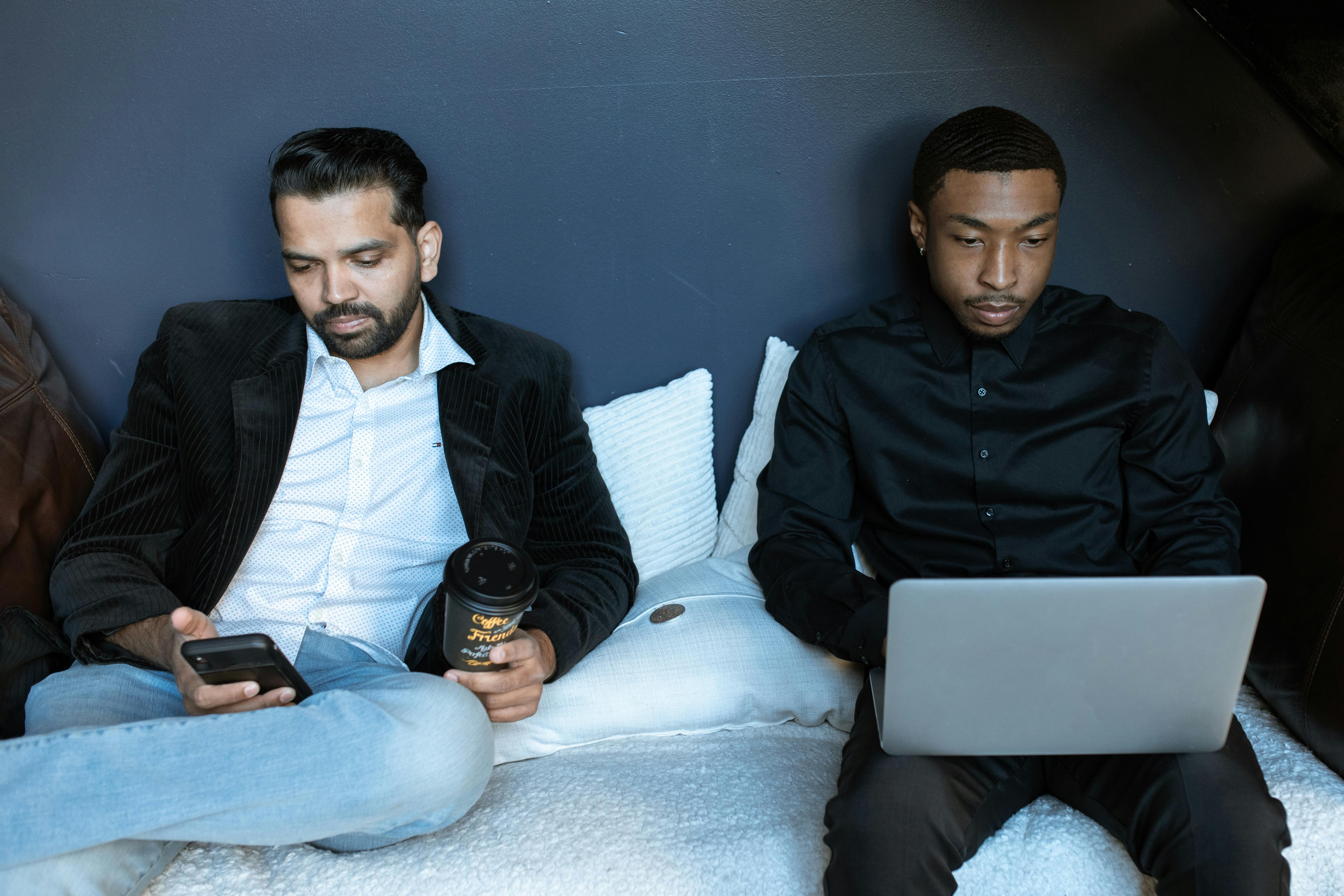 man in black jacket sitting on couch beside man in black jacket