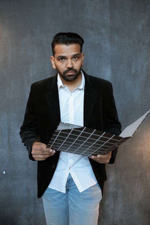 Man in Black Suit Jacket Holding Black Folder while Looking at the Camera