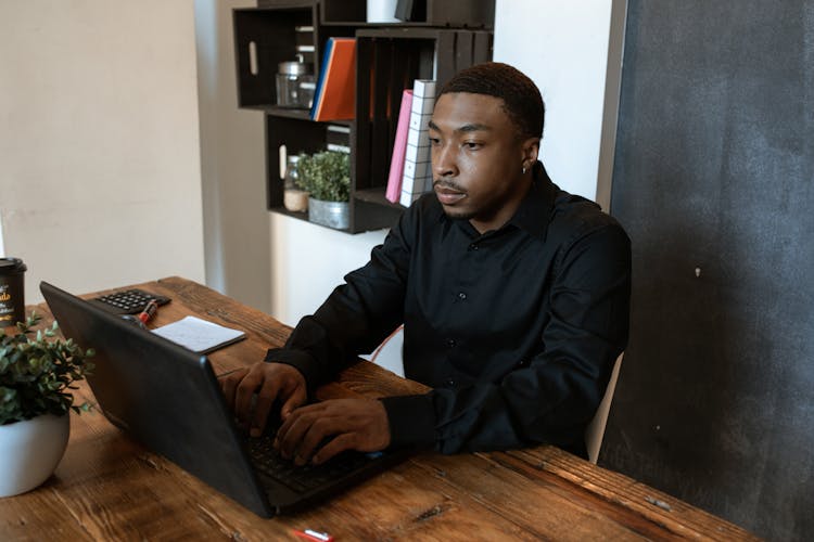 A Man In Black Long Sleeves Typing On Laptop