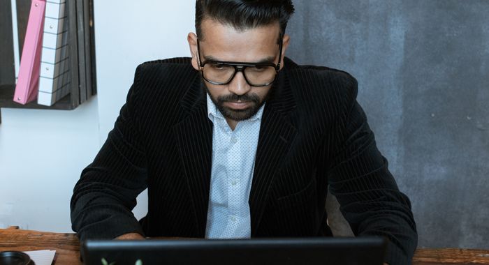 A founder working at a desk with a laptop and a plant