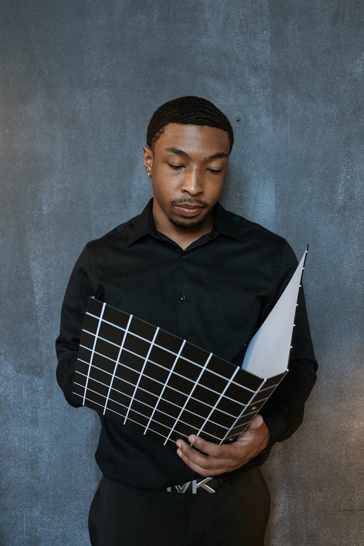 A Man In Black Long Sleeves Holding A Binder