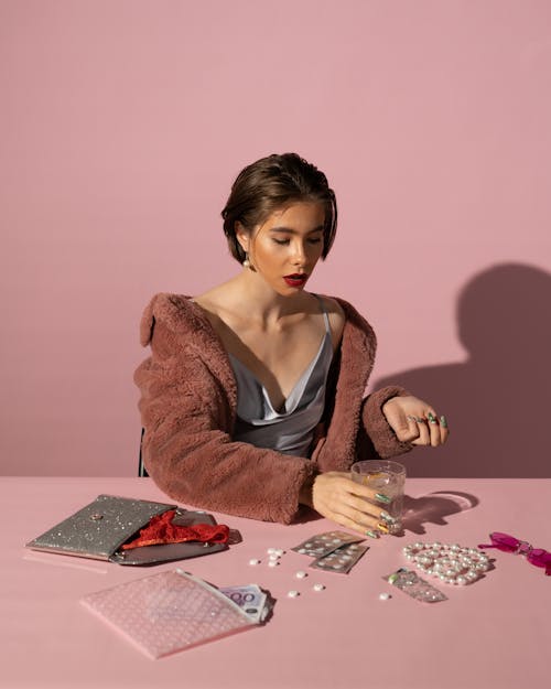 Free Woman in Brown Fur Coat Sitting at Tables with Pills Stock Photo