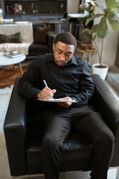 Focused man writing in notepad while sitting in modern home office.