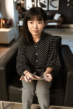 办公室里，一位亚洲女性手拿平板电脑，准备面试