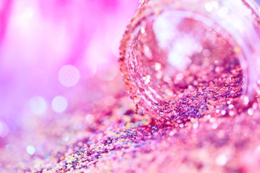 A close-up of pink and violet glitter spilling from a jar with bright bokeh effects.