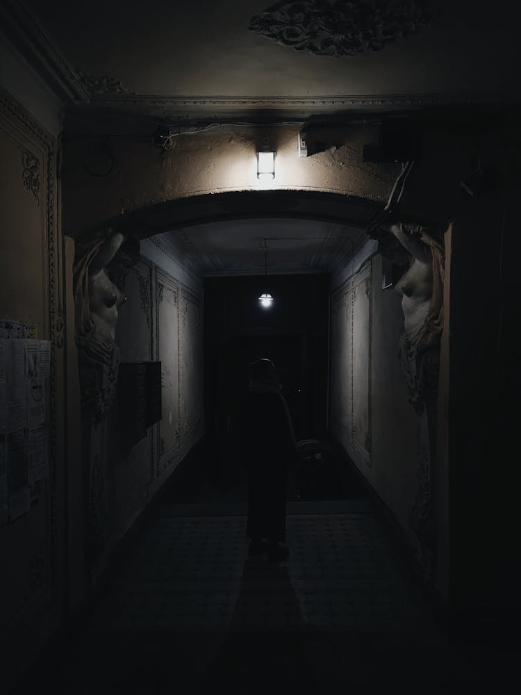 Person Standing In A Hallway In A Dark Room