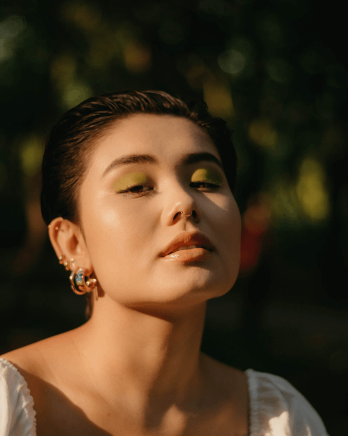 Free Close-up portrait of a young woman outdoors with natural light highlighting her makeup and accessories. Stock Photo
