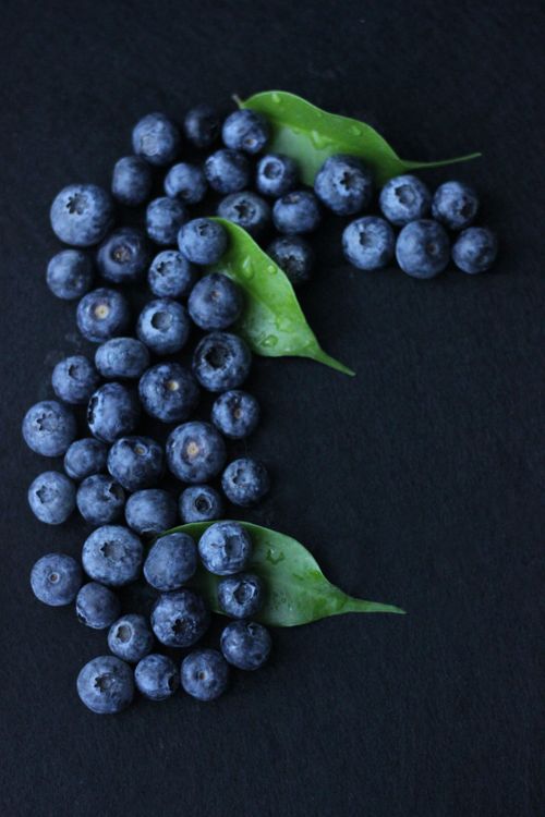 Free Close-up of fresh, wet blueberries with green leaves on a dark surface, top view. Stock Photo
