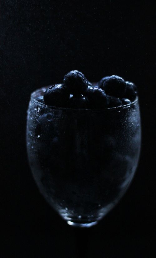 Free A dramatic close-up shot of fresh blueberries in a glass against a black background. Stock Photo