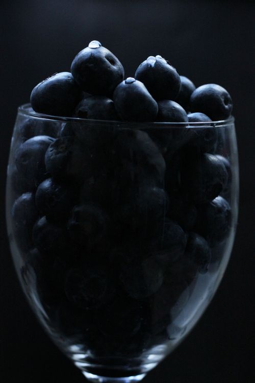 Free A moody still life of fresh blueberries in a glass against a dark background. Stock Photo