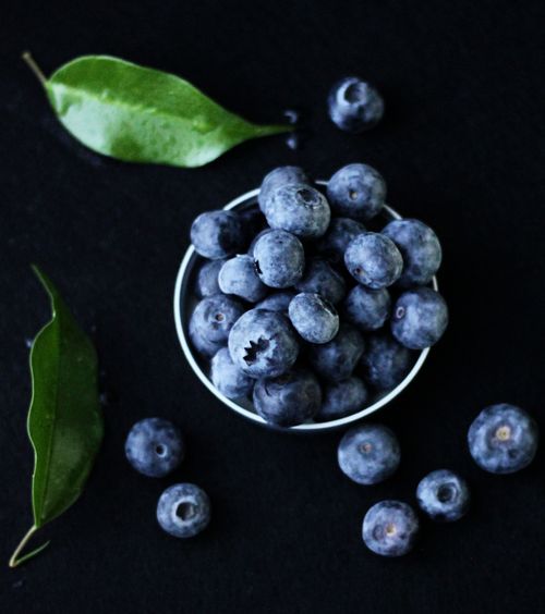 Free Close-up of ripe blueberries in a cup surrounded by green leaves, showcasing freshness and vitamins. Stock Photo