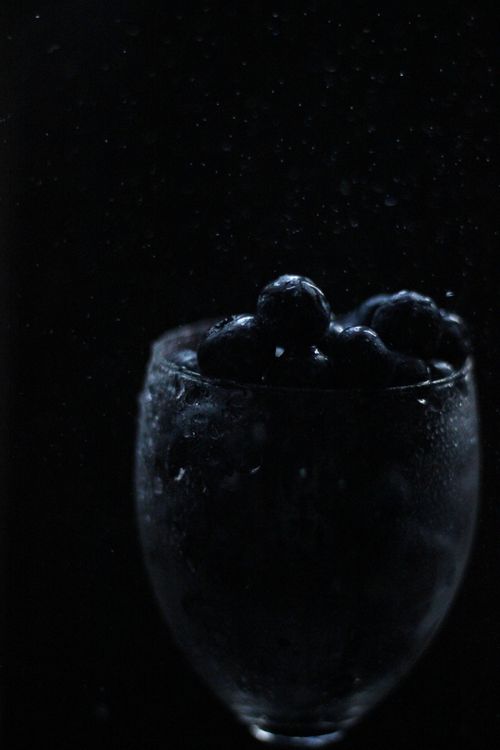 Free Fresh blueberries glistening with moisture in a wine glass against a dark background, creating a moody vibe. Stock Photo