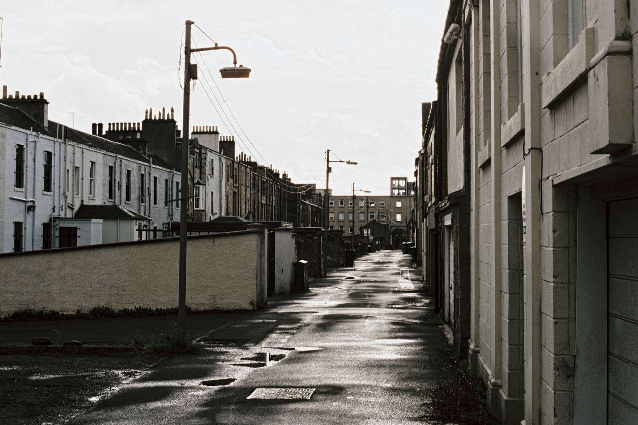 a nostalgic view of a wet empty city street lined with classic buildin