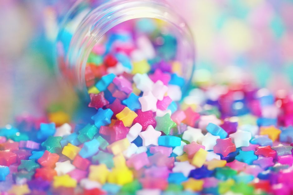 Vibrant close-up of colorful star-shaped candies in rainbow hues, spilling from a jar.