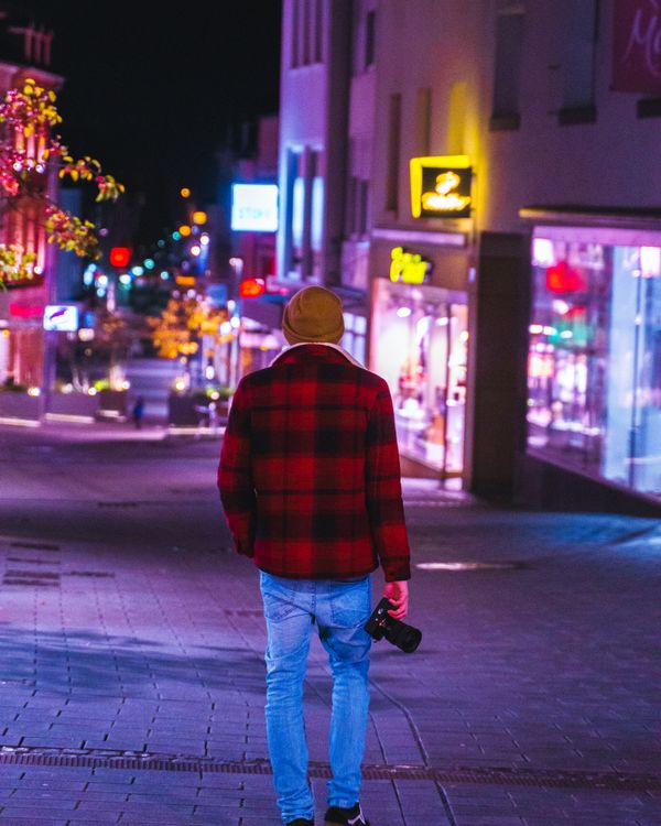 Man Walking Through a City at Night with a Camera · Free Stock Photo