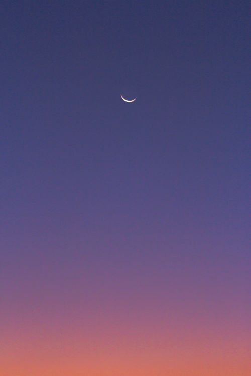 Free A mesmerizing crescent moon set against a vibrant gradient evening sky with purple hues. Stock Photo