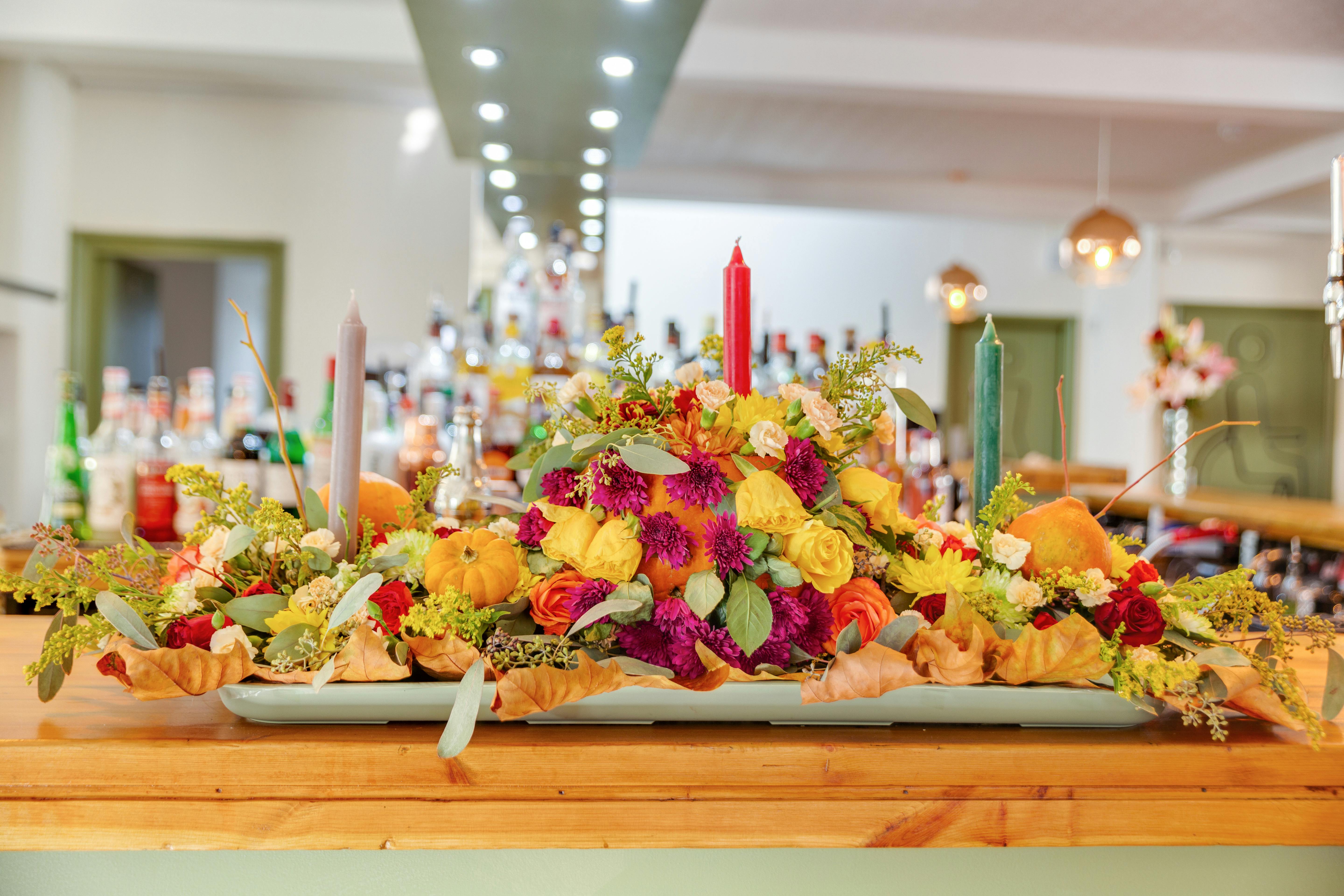 Elegant flower arrangement with vibrant autumn colors and candles, perfect for festive celebrations.