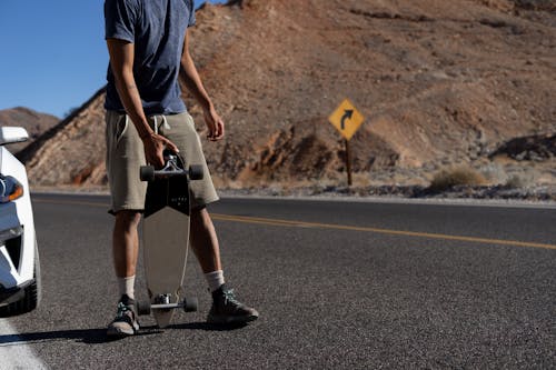 Free Man with a Longboard Standing on Roadside  Stock Photo