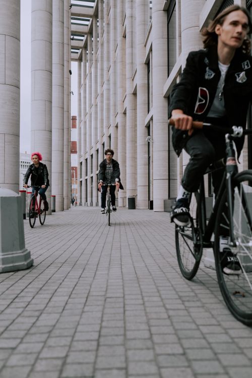 Free Three friends ride bicycles on a city street, showcasing urban lifestyle and commute. Stock Photo