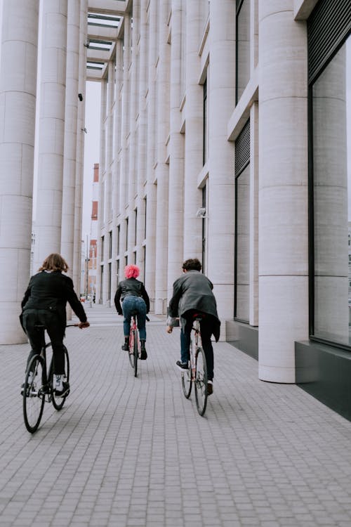 бесплатная Мужчина и женщина, езда на велосипеде на белом бетонном здании Стоковое фото
