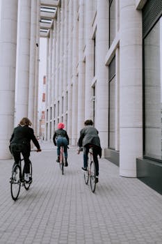 Group of people cycling along a column-lined walkway in the city.