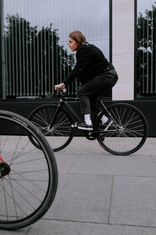 검은 정장 재킷과 바지를 입고 검은 자전거를 타는 남자