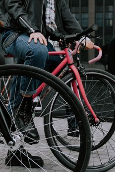 Close-up of a cyclist wearing denim jeans riding a fixie bike in an urban setting.