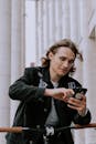 A Man in Black Jacket Holding a Black Smartphone