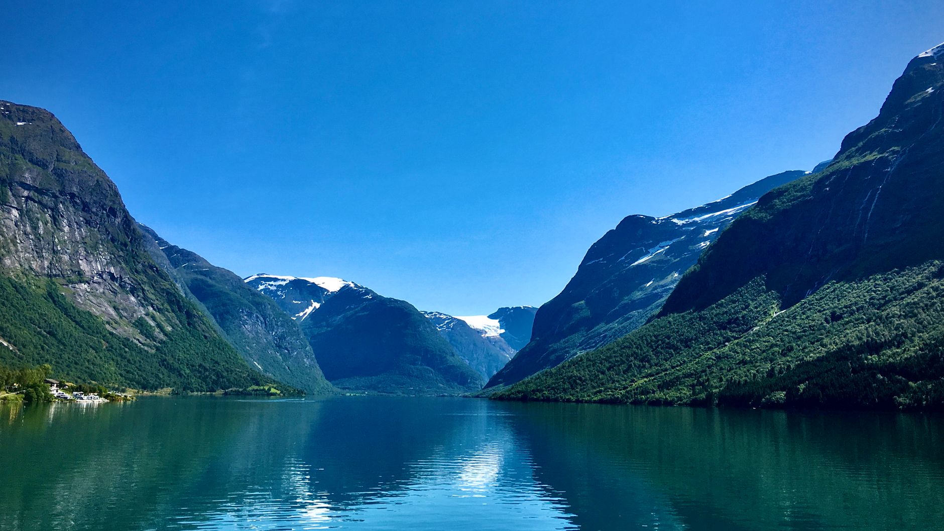 Discover the serene beauty of a Norwegian fjord with snow-capped mountains and a clear blue lake.