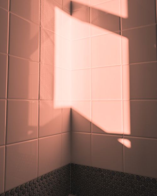 Free A serene minimalist shot showcasing sunlight reflecting on a tiled corner wall, creating a warm atmosphere. Stock Photo