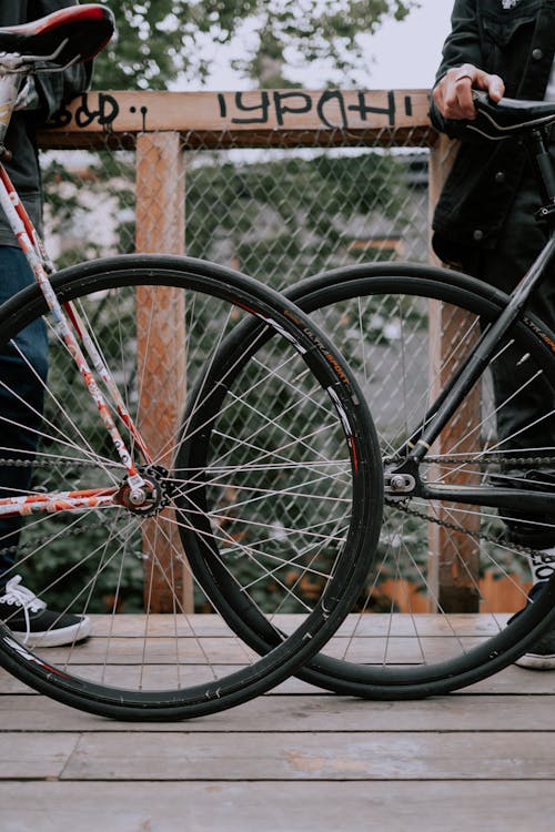 Rueda De Bicicleta Negra Recostada Sobre Valla Metálica Marrón