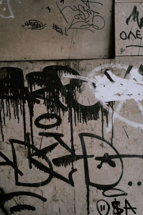Free Close-up of black graffiti on a worn concrete wall, showcasing street art. Stock Photo