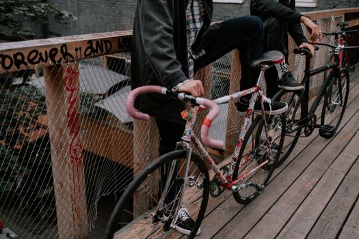 两名穿着休闲牛仔布的人在涂鸦桥上装饰着自行车