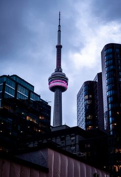 Stunning view of Toronto's CN Tower surrounded by skyscrapers against a cloudy dusk sky.