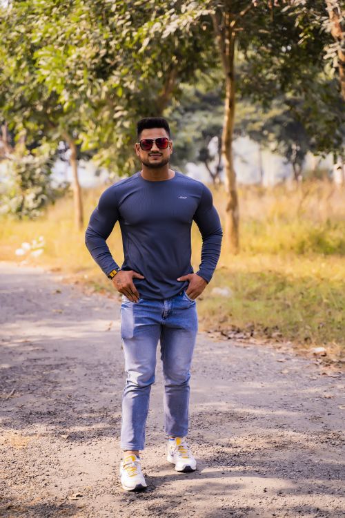 Free A stylish young man posing confidently in a natural outdoor setting with modern fashion wear. Stock Photo