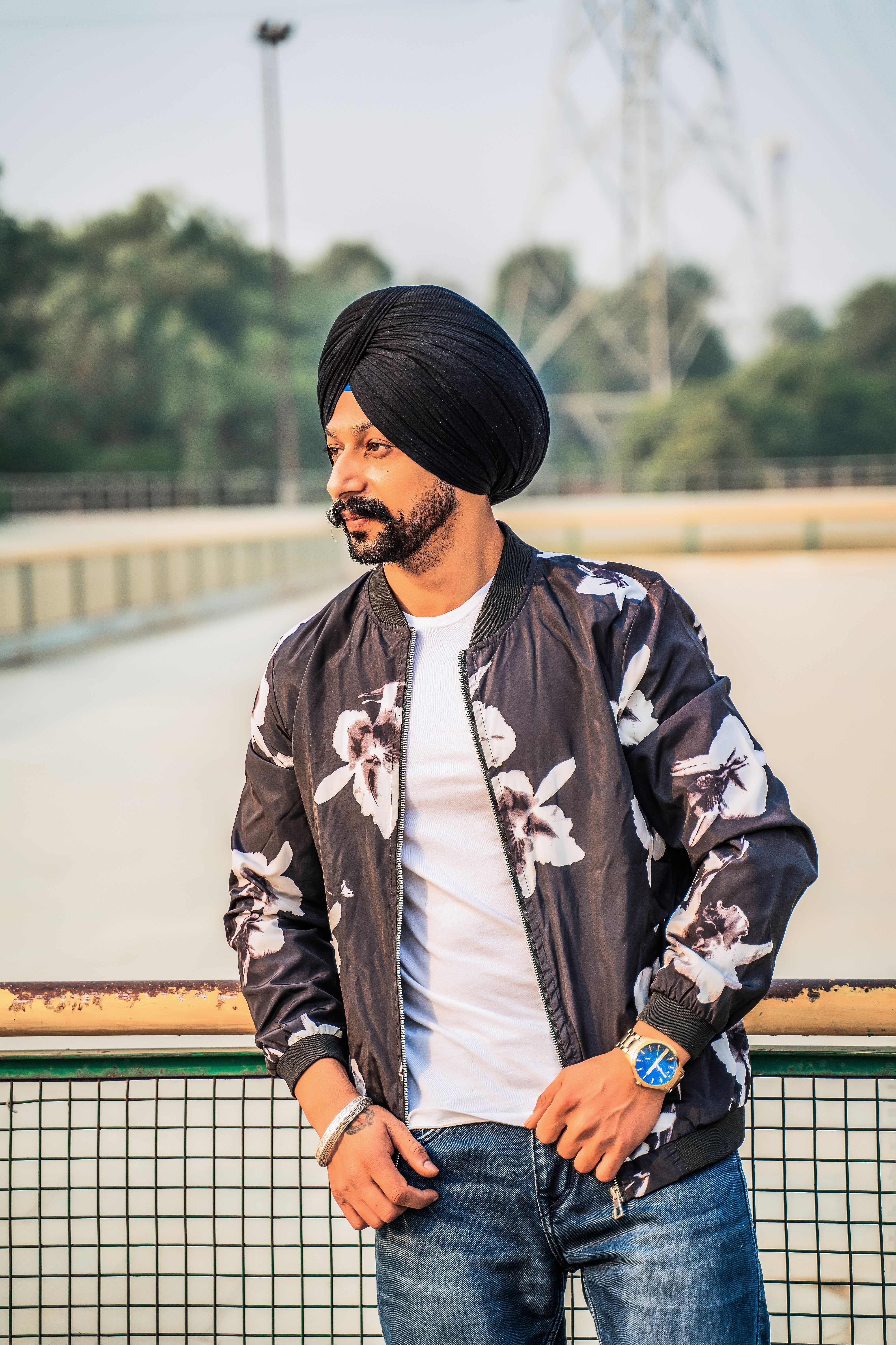 Stylish man in a floral jacket and turban posing outdoors, showcasing casual fashion.