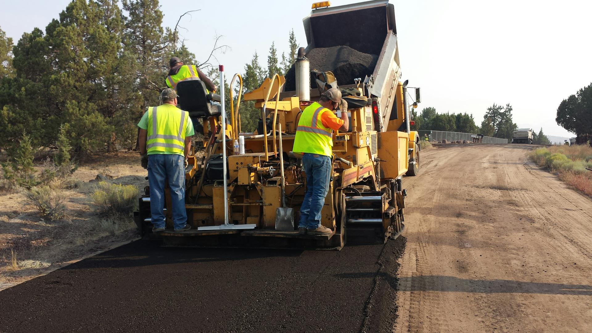 Workers paving a road in Redmond, Oregon with heavy equipment.