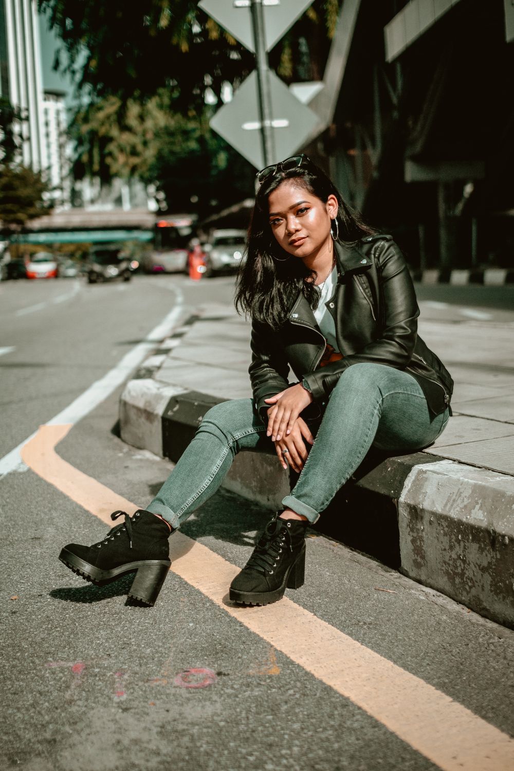 Woman in Black Leather Jacket Sitting on Sidewalk · Free Stock Photo
