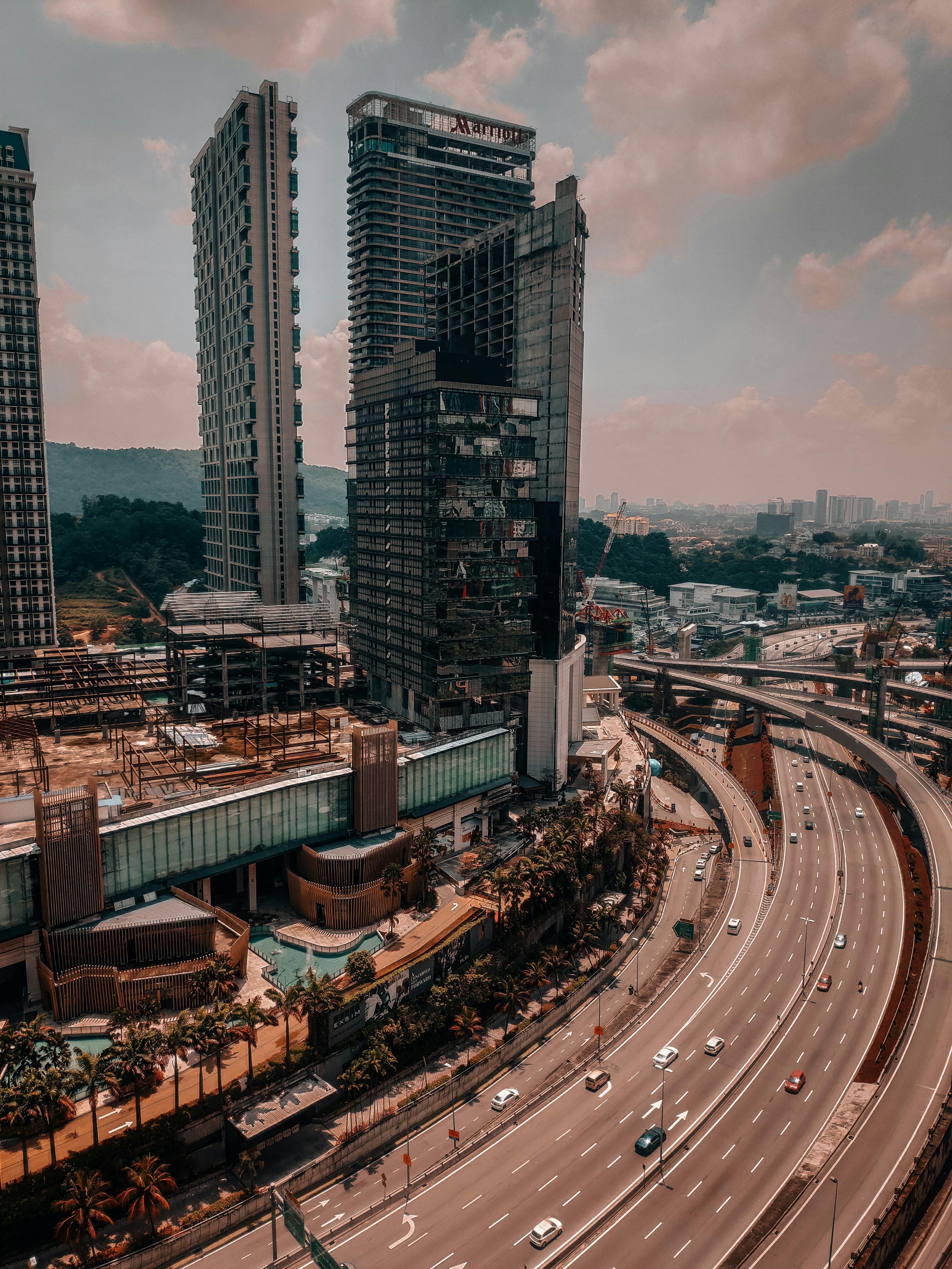 Aerial view of a city skyline with skyscrapers and highway at dusk, capturing the vibrant urban atmosphere.
