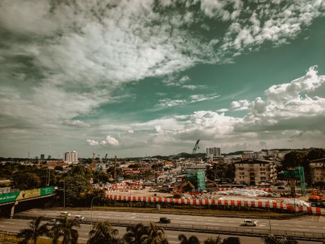 A vibrant cityscape with ongoing construction under a dramatic cloudy sky.