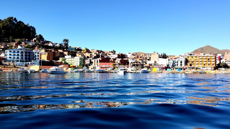 Vue vibrante du littoral de Copacabana avec des bateaux sur le lac Titicaca sous un ciel bleu clair.