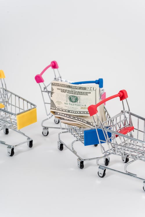 Close-Up Photo Of Money and Miniature Shopping Carts