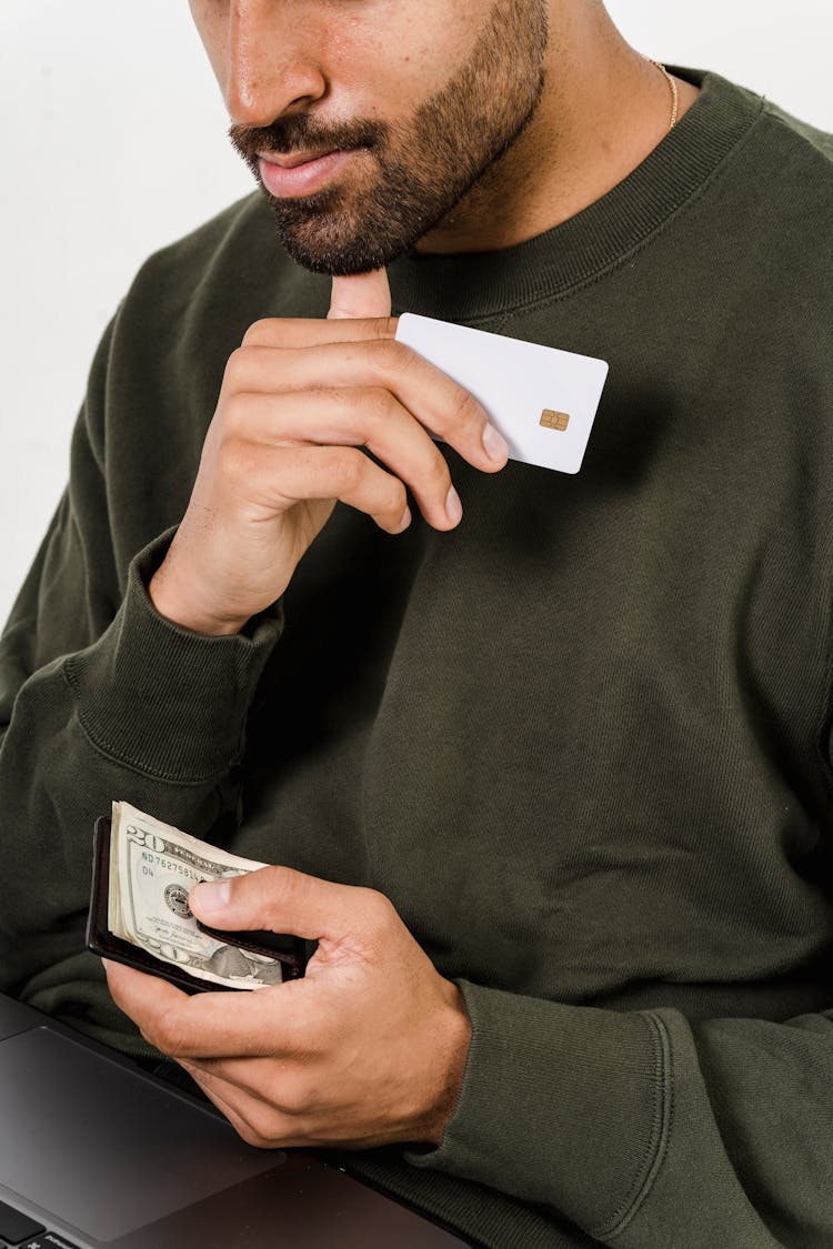 A Man Holding A Bank Card And Dollar Bills