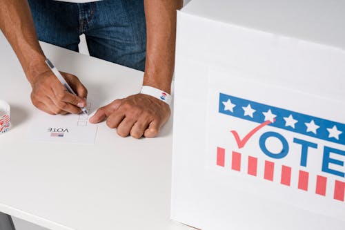 Free A Person with a Wristband Casting a Vote Stock Photo